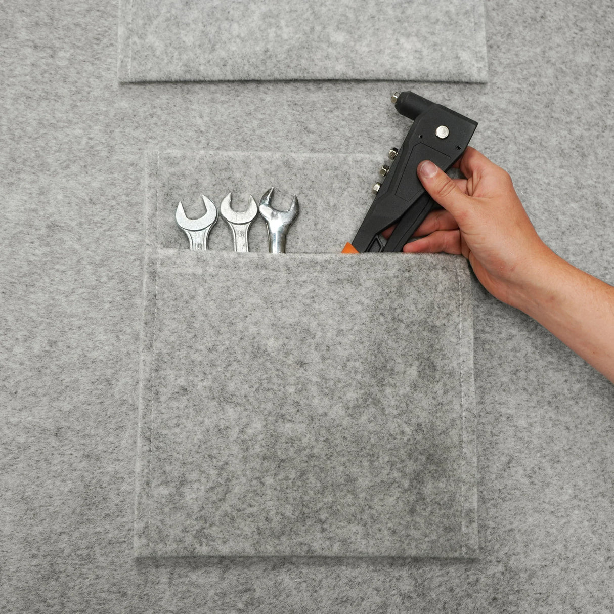 Silver grey van carpet lining with storage pouches, showcasing tools like wrenches and a glue gun in a soft, textured material