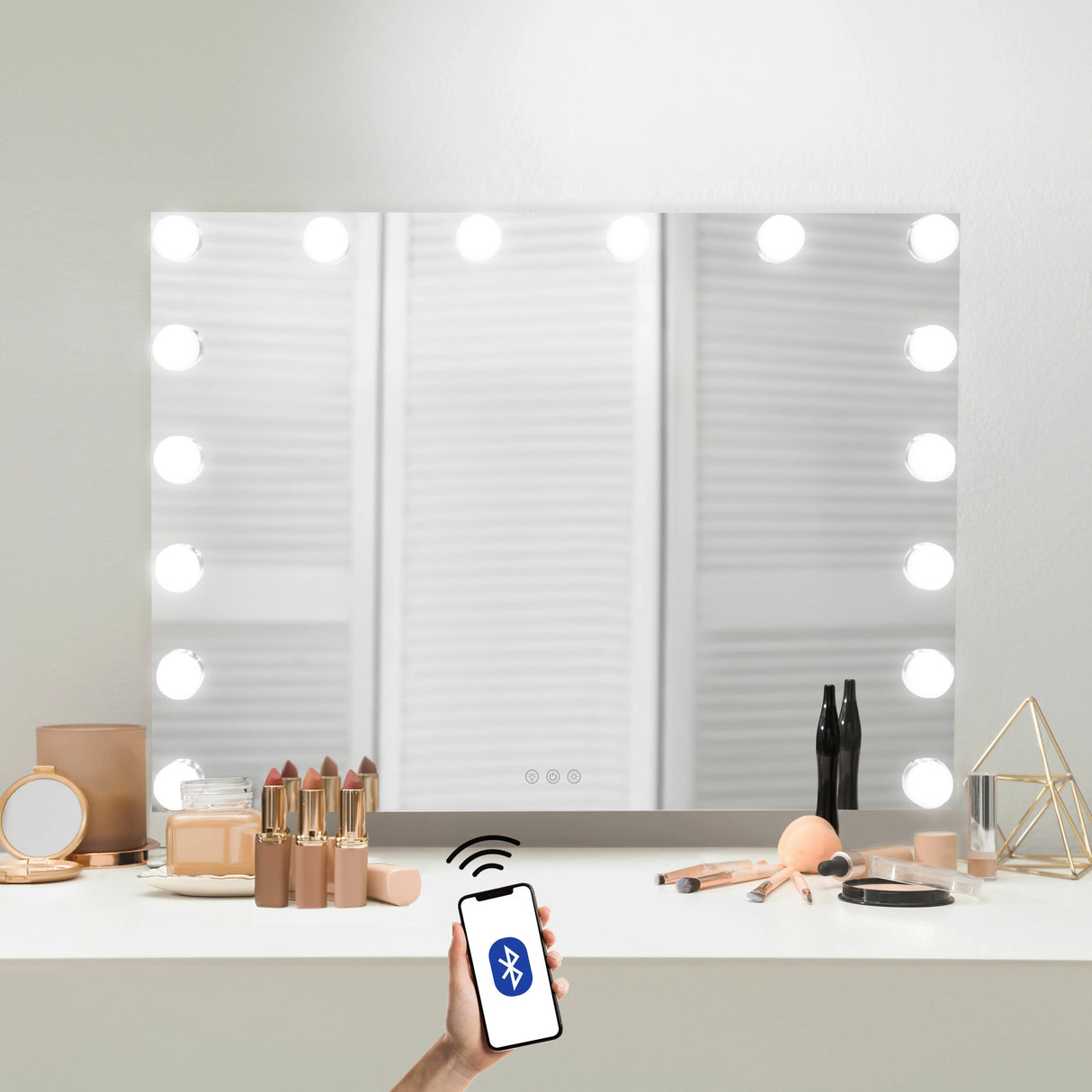 LED Bluetooth mirror 80 x 60cm with bright round bulbs, sleek glass surface, and a hand holding a smartphone for remote control