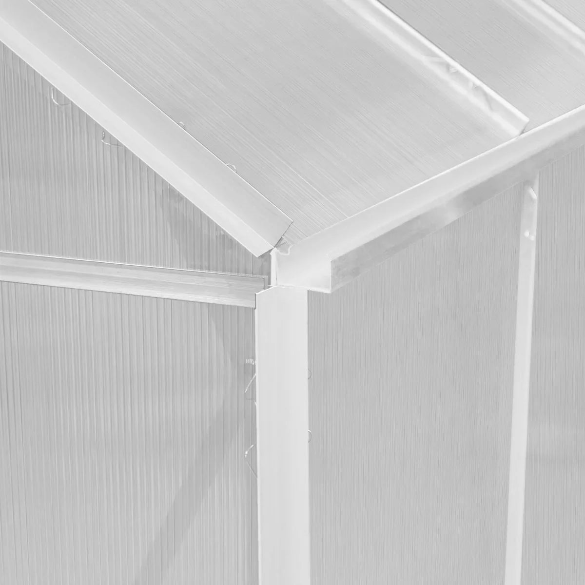 Close-up of the silver polycarbonate greenhouse's corner joint, showcasing its sturdy frame and transparent, ribbed panels