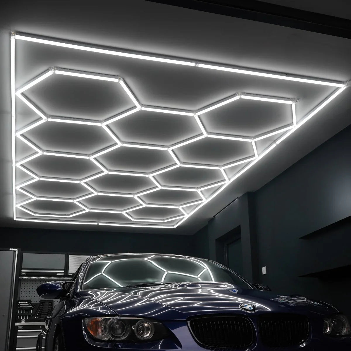 Hexagon LED lighting in a modern garage, featuring sleek white neon tubes arranged in a honeycomb pattern above a blue car