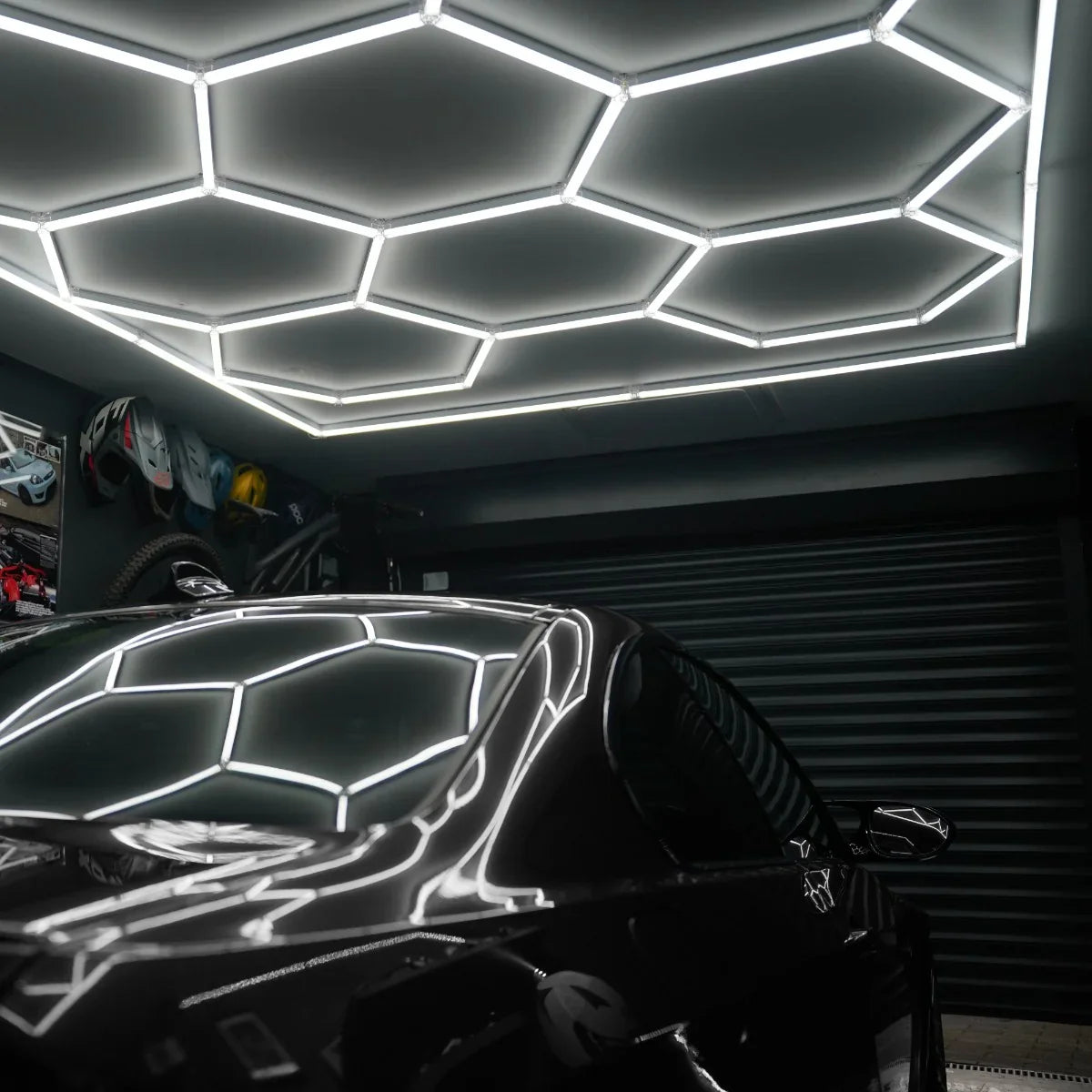 Hexagon LED lighting panels illuminate a sleek black car, creating a modern, stylish ambiance in a garage setting