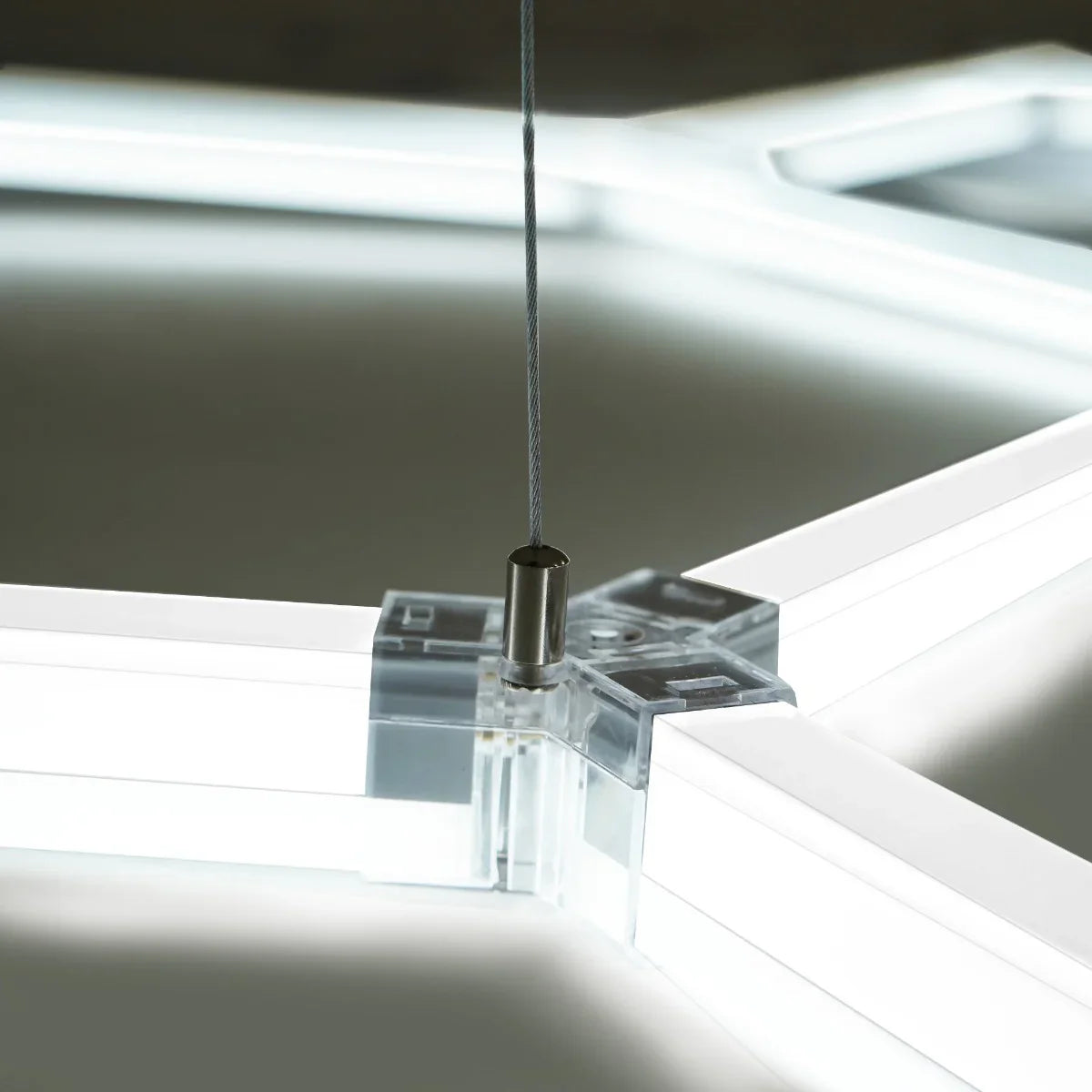 Close-up of a hexagon LED light fixture showing clear acrylic connectors and bright white illumination, highlighting modern design