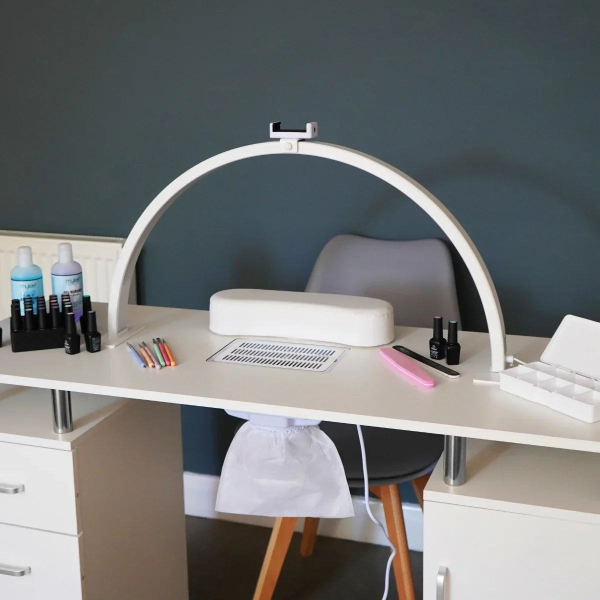 Sleek LED Half Moon Lamp in white, arching over a modern nail station with colorful nail polish and tools on a minimalist desk