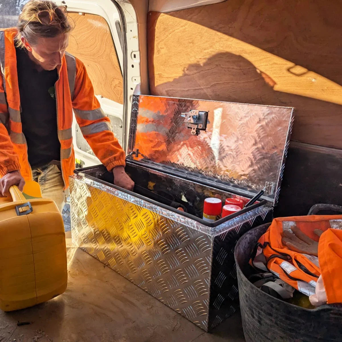 Large 70L aluminium tool box with a diamond plate finish, open to reveal tools inside, placed in a van with safety gear nearby