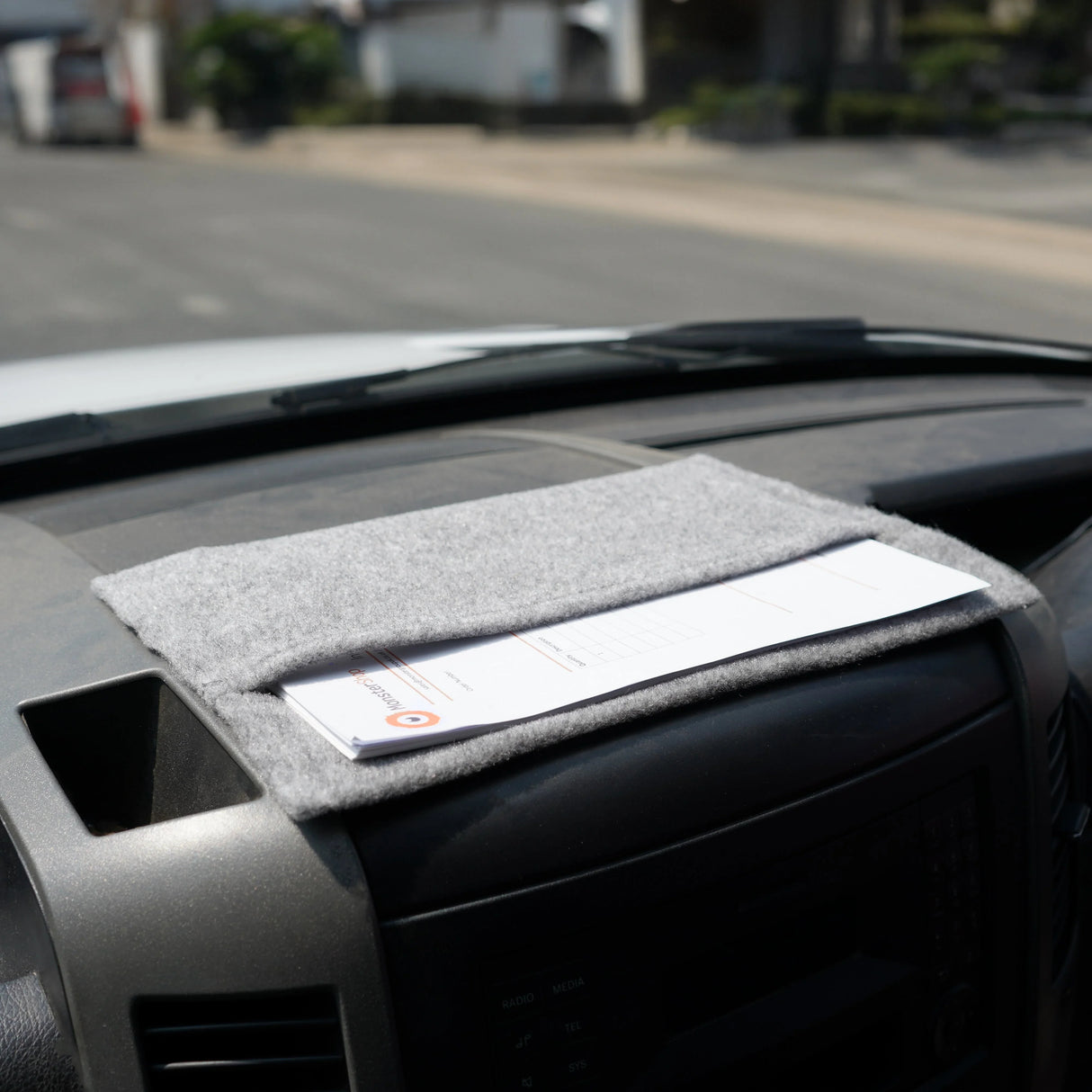 Silver grey storage pouch made of soft felt, neatly placed on a vehicle's dashboard, holding documents securely in place