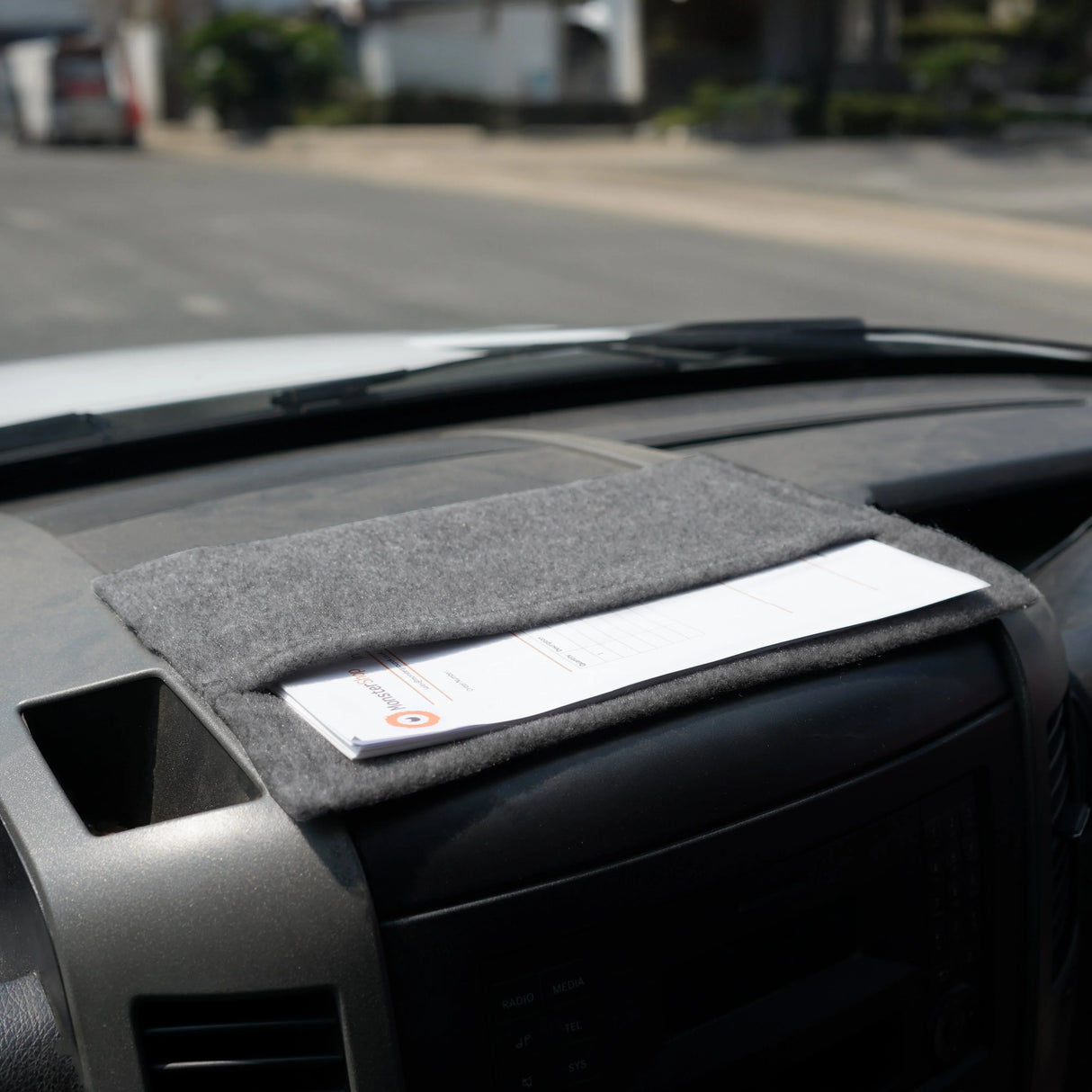 Smoke grey storage pouch made of soft felt, neatly holding documents on a vehicle dashboard, showcasing its practical design