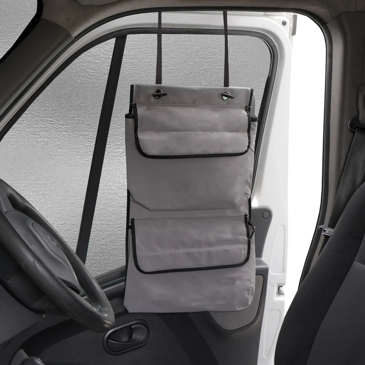 Gray motorhome screen cover with multiple pockets, hanging from the vehicle's interior, designed for sun protection and privacy