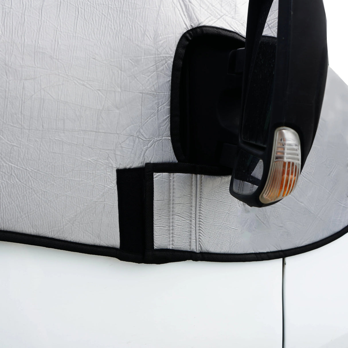 Silver motorhome screen cover with textured surface, fitted snugly around the side mirror, featuring a secure fastening strap