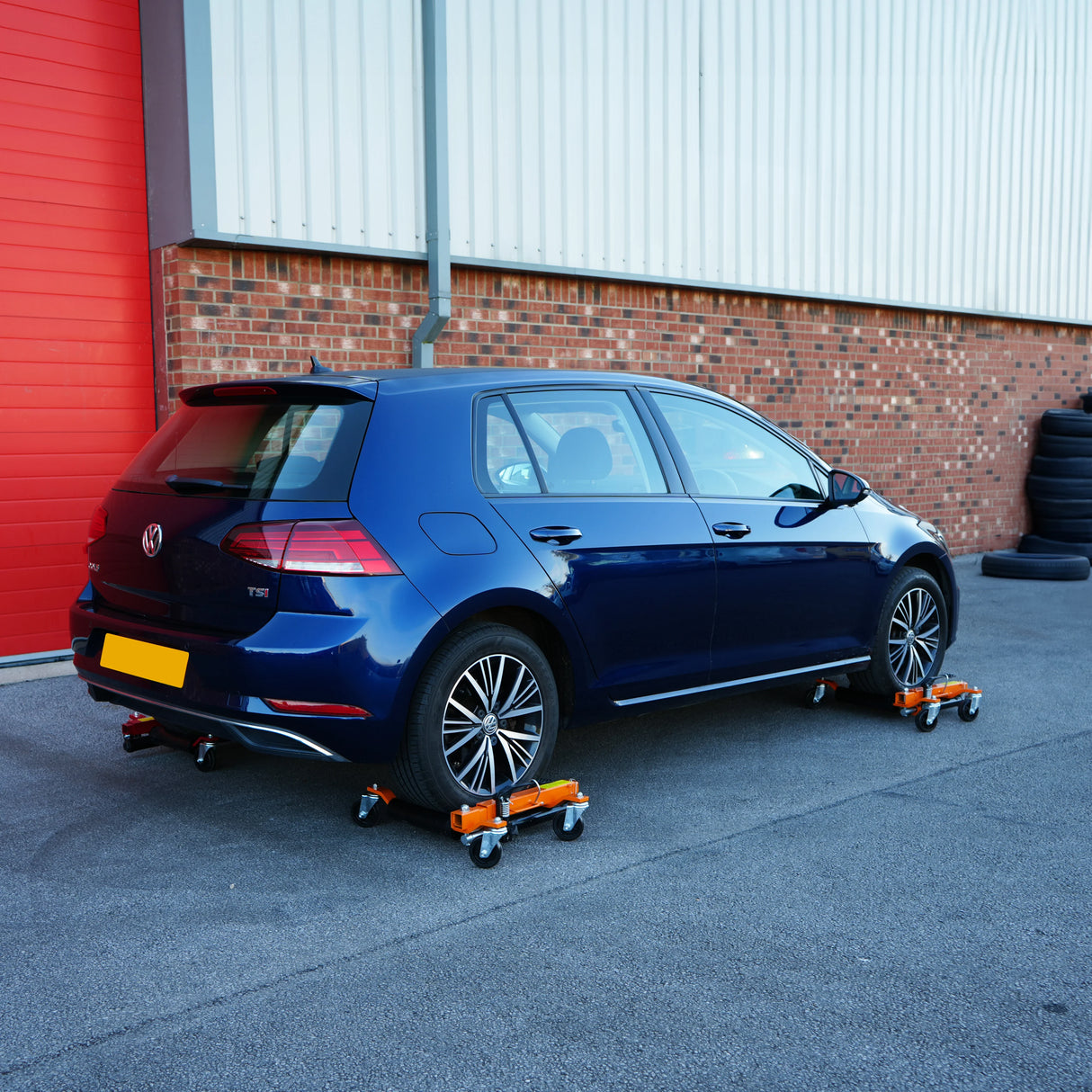 Hydraulic positioning skates pair under a blue Volkswagen Golf, showcasing sturdy wheels and a robust design for easy vehicle maneuvering