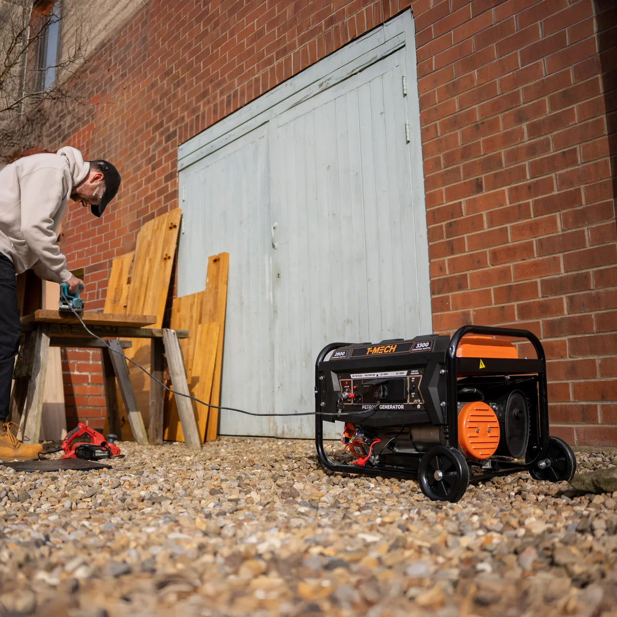 T-Mech Portable Petrol Generator on wheels, featuring a black and orange design, with a user connecting it to a power source outdoors