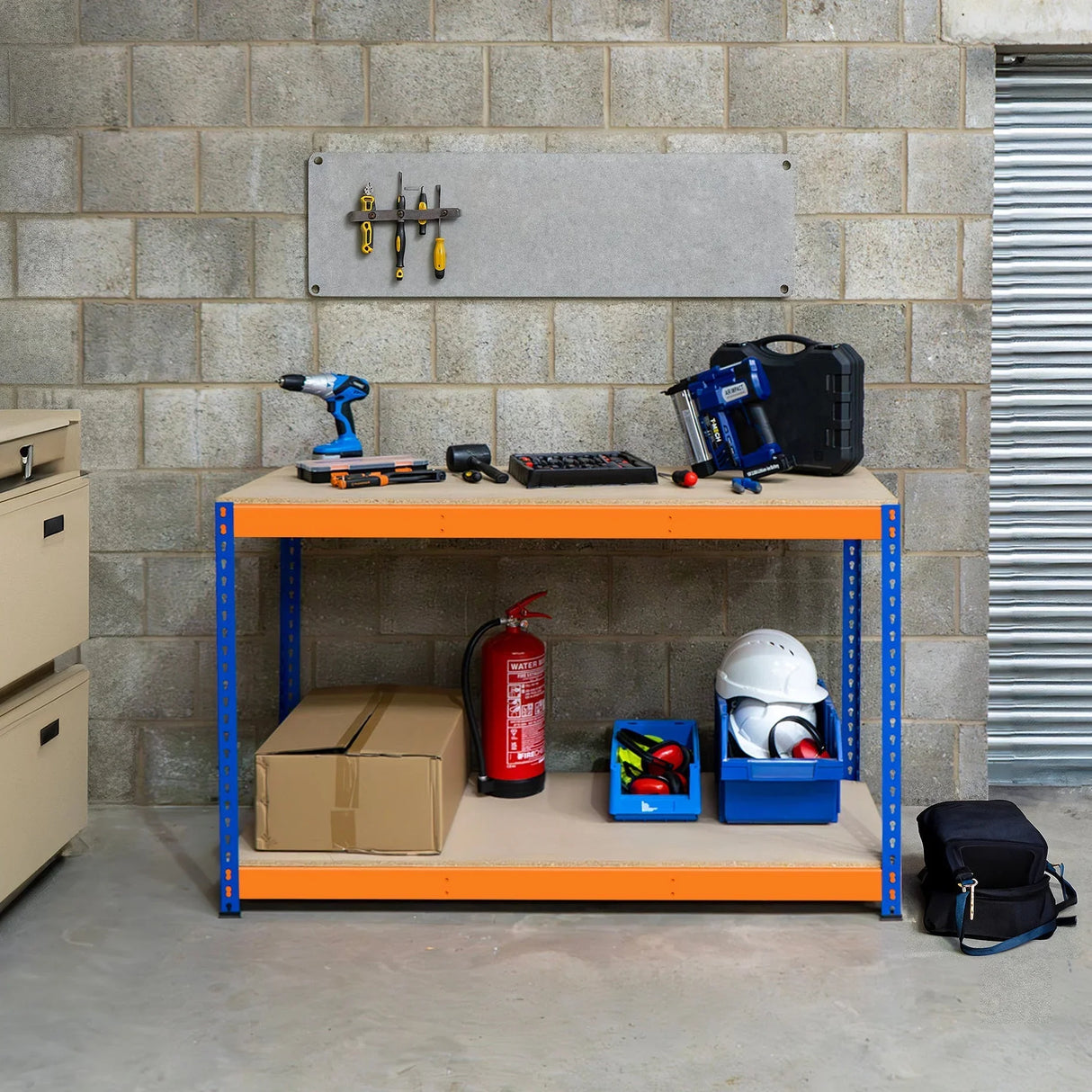 S-Rax 2 Tier Workbench in blue and orange with tools, storage boxes, and safety gear on a textured concrete background