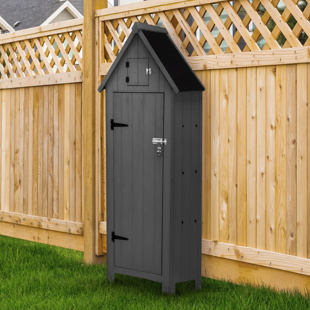 Dark grey wooden garden shed with a peaked roof, double doors, and a small upper storage compartment, set against a wooden fence