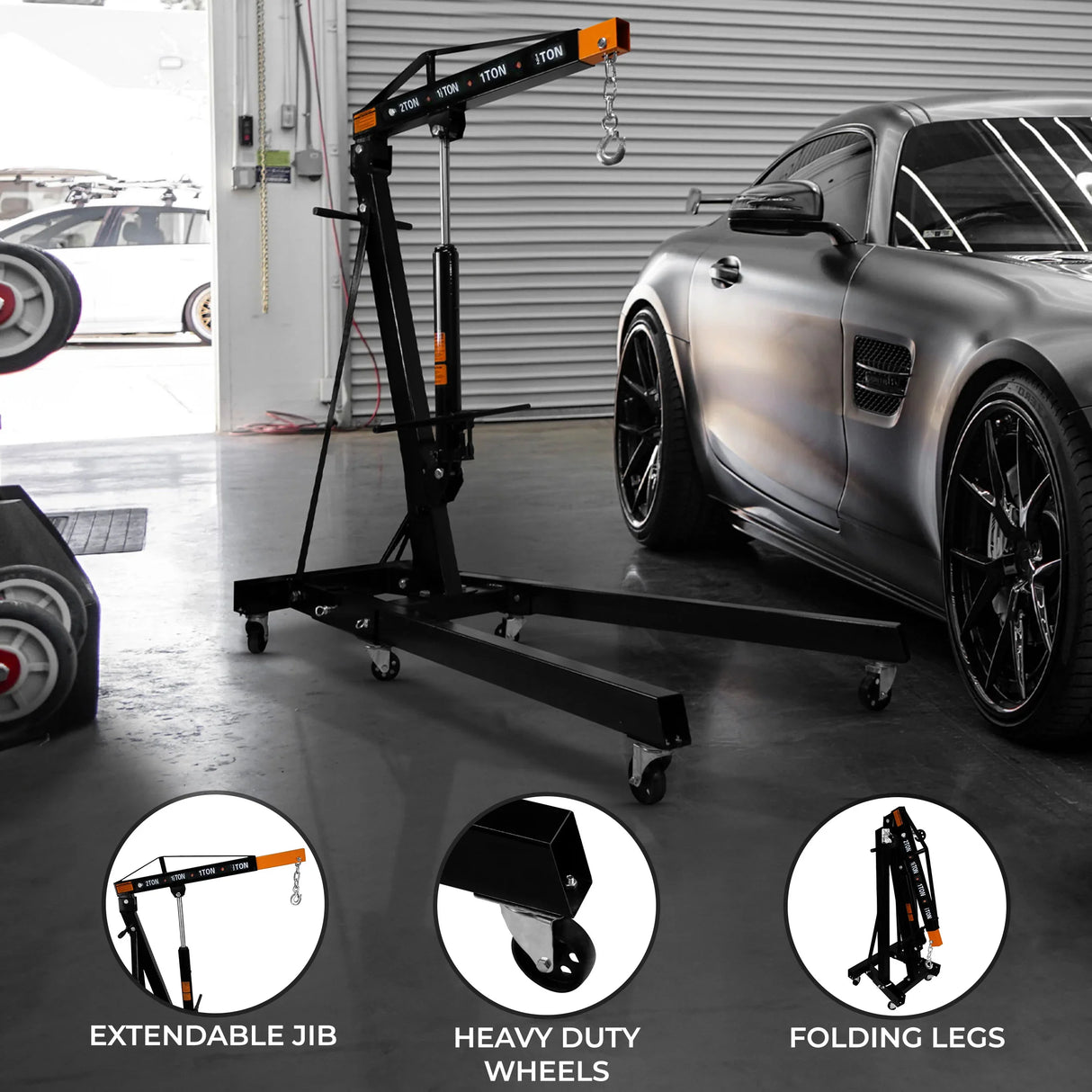 Hydraulic engine crane with extendable jib, heavy-duty wheels, and folding legs, set against a sleek car in a garage environment