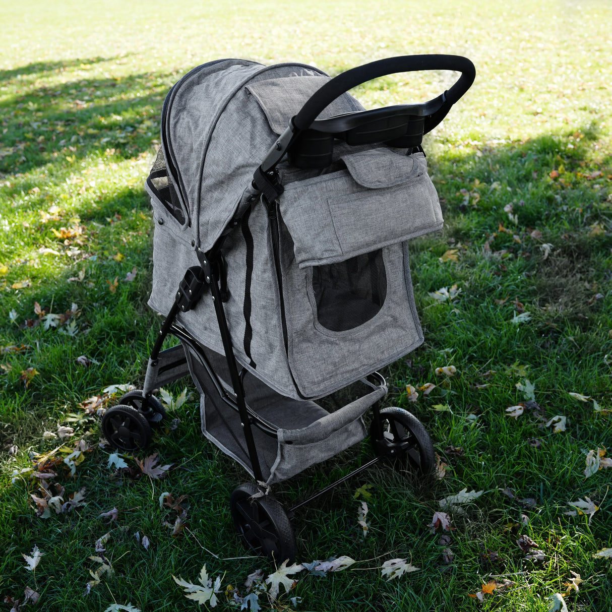 Woven grey pet stroller caddy bag with mesh window, spacious storage, and sturdy wheels, set against a grassy outdoor background