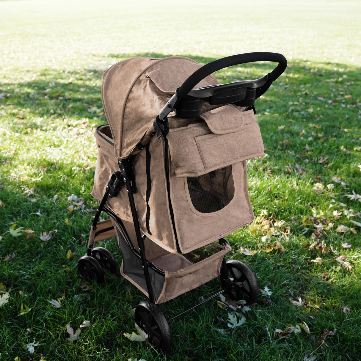 Woven beige pet stroller caddy bag with a mesh window, sturdy frame, and spacious storage, set on green grass with fallen leaves