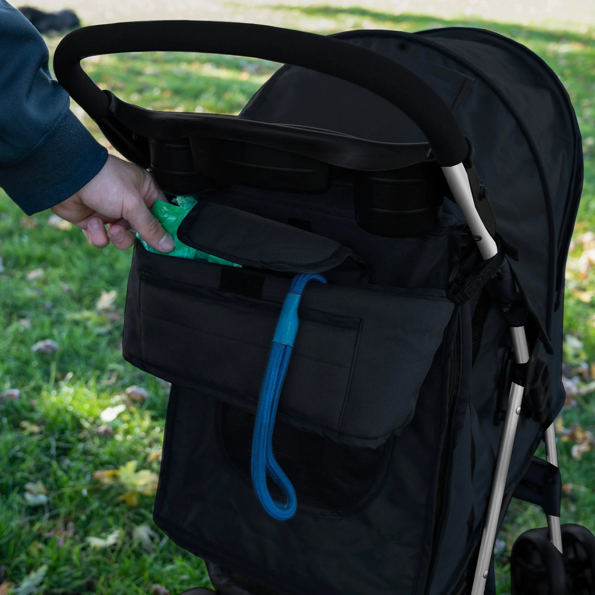 Black pet stroller caddy bag featuring multiple pockets, a sleek design, and a convenient leash attachment for easy access