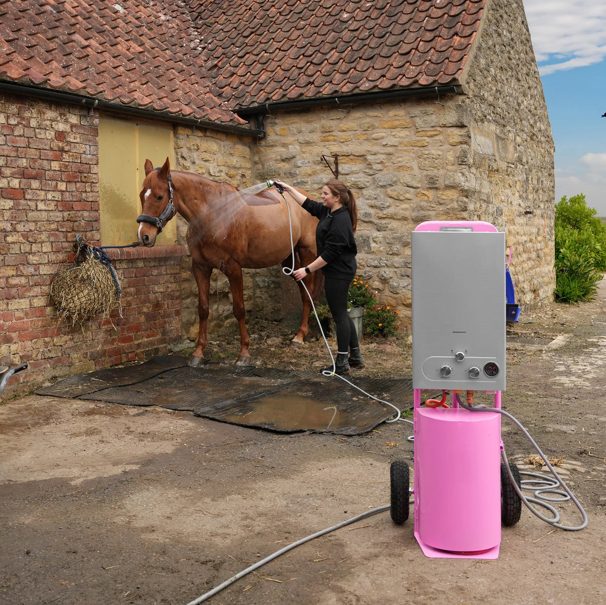 Deluxe Portable Horse Shower in pink, featuring a sleek design, wheels for mobility, and a user washing a horse outdoors