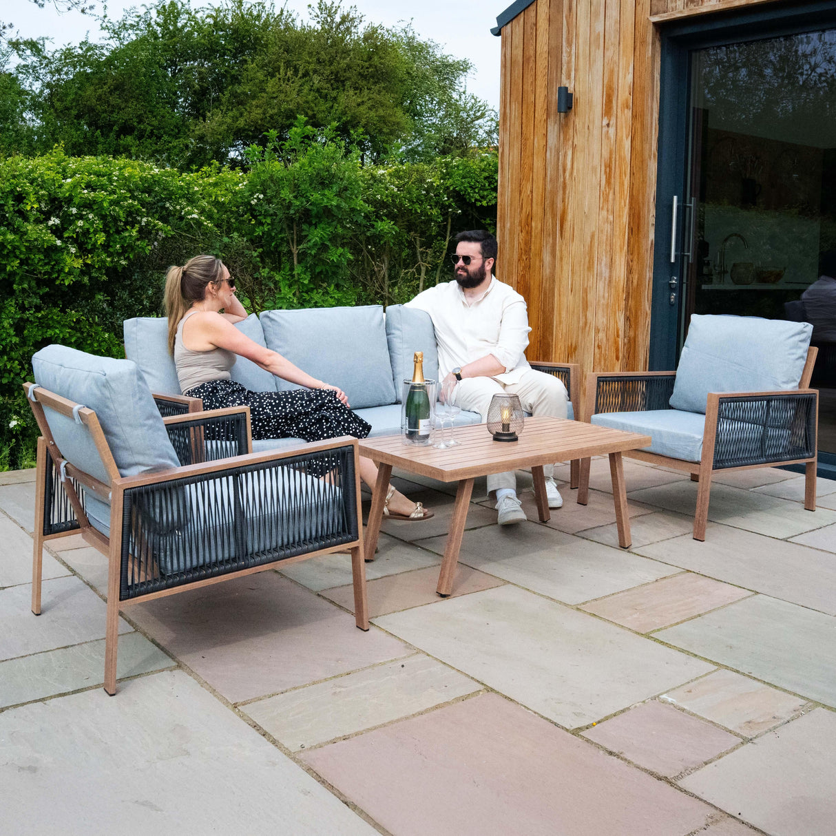 Aluminium 4 piece sofa set with wood effect, featuring light blue cushions, sleek design, and a matching coffee table, perfect for outdoor lounging
