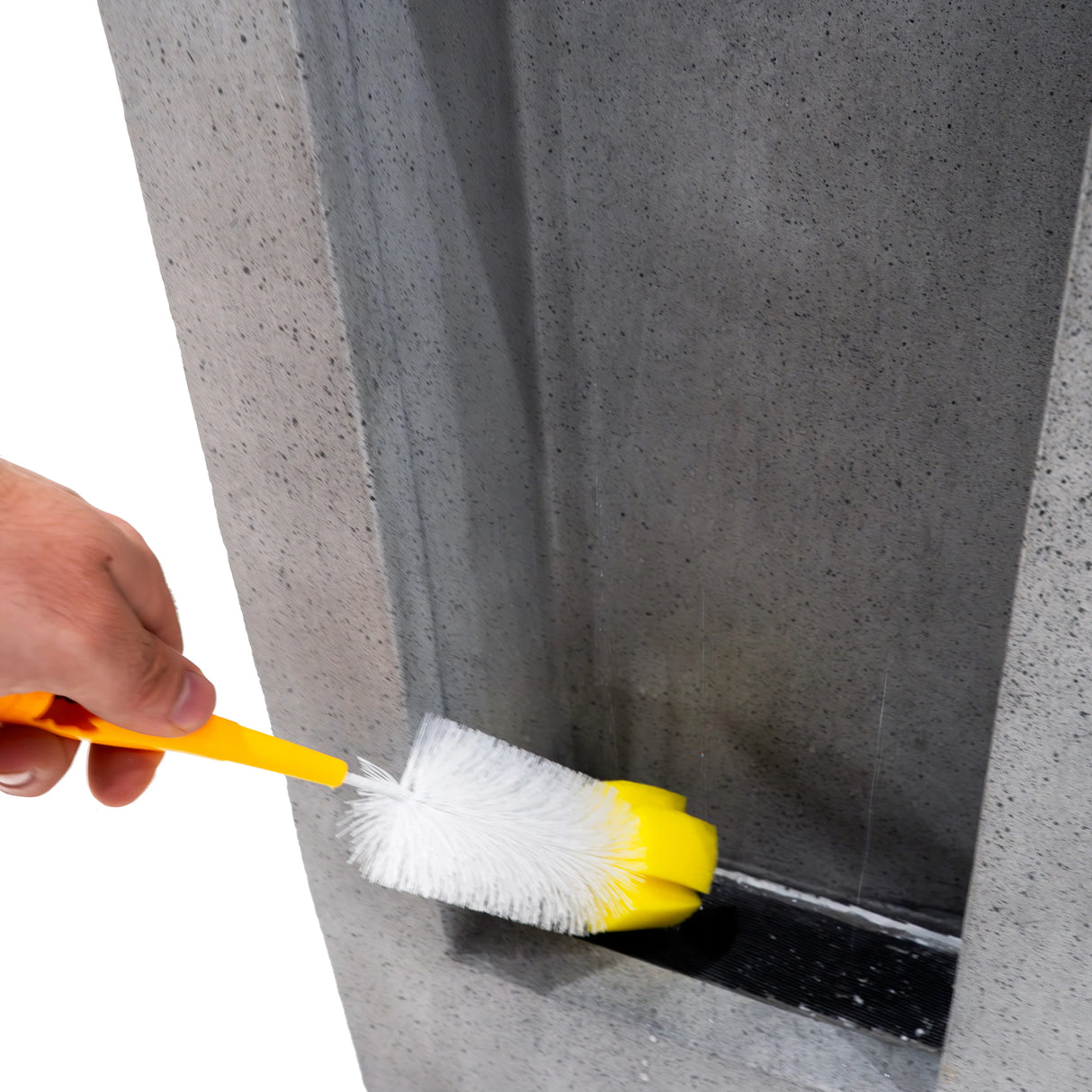 Cleaning the Electric Water Feature - Serenity Falls with a yellow brush, highlighting its sleek concrete design and water flow area