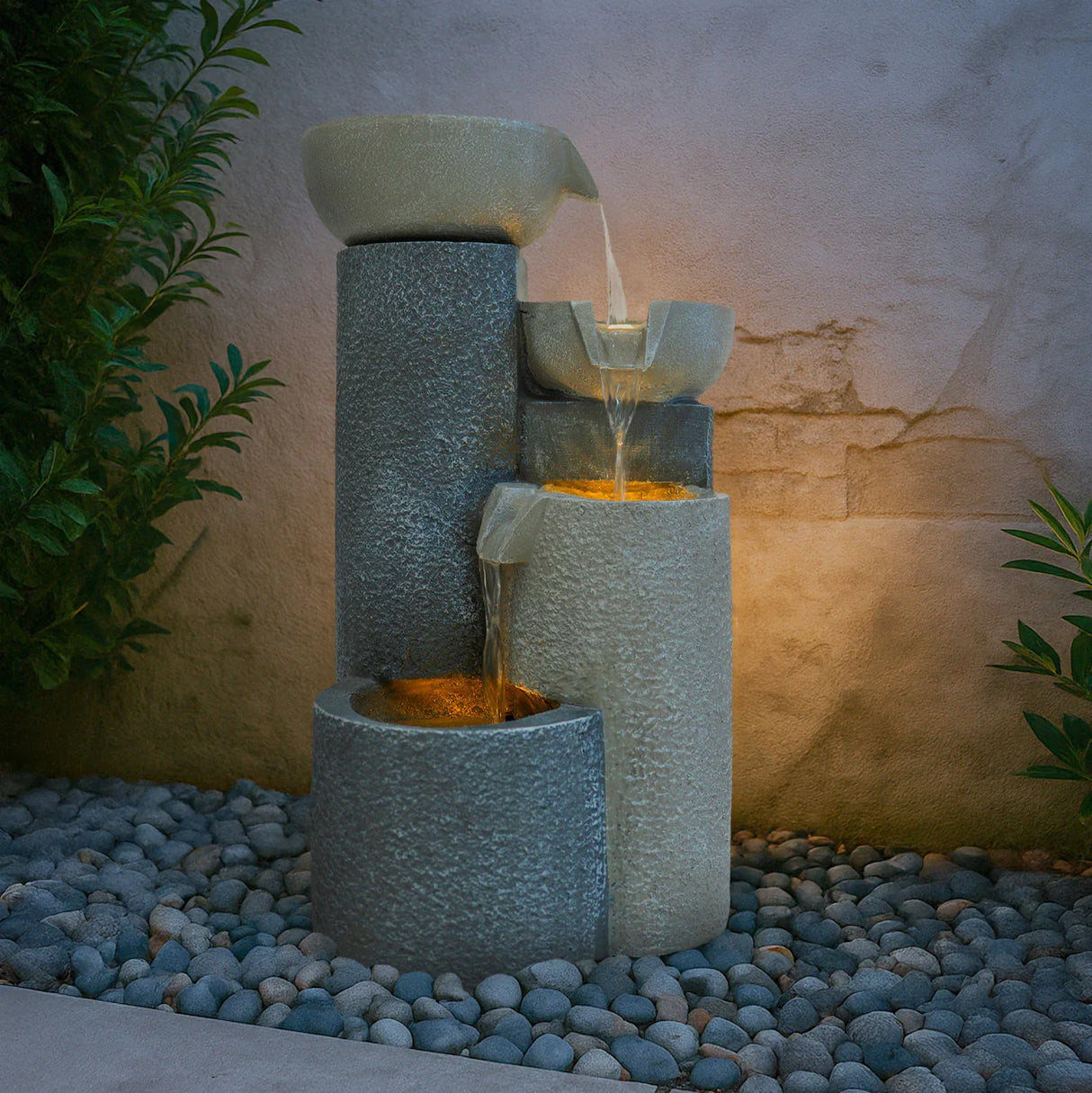 Tranquil Tiers electric water feature with three textured stone-like tiers, cascading water, and soft ambient lighting on pebbled base