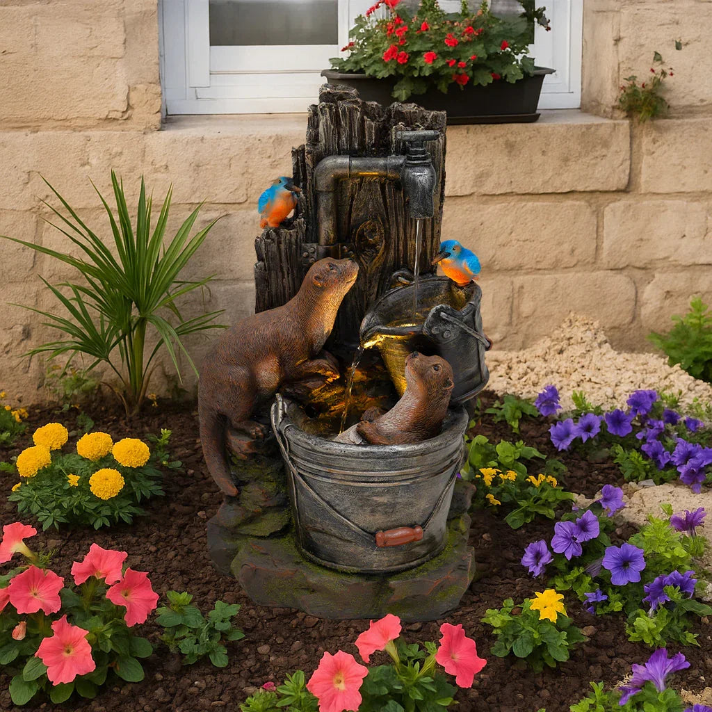Electric water feature featuring playful otters beside a rustic bucket, surrounded by vibrant flowers and greenery in a garden setting
