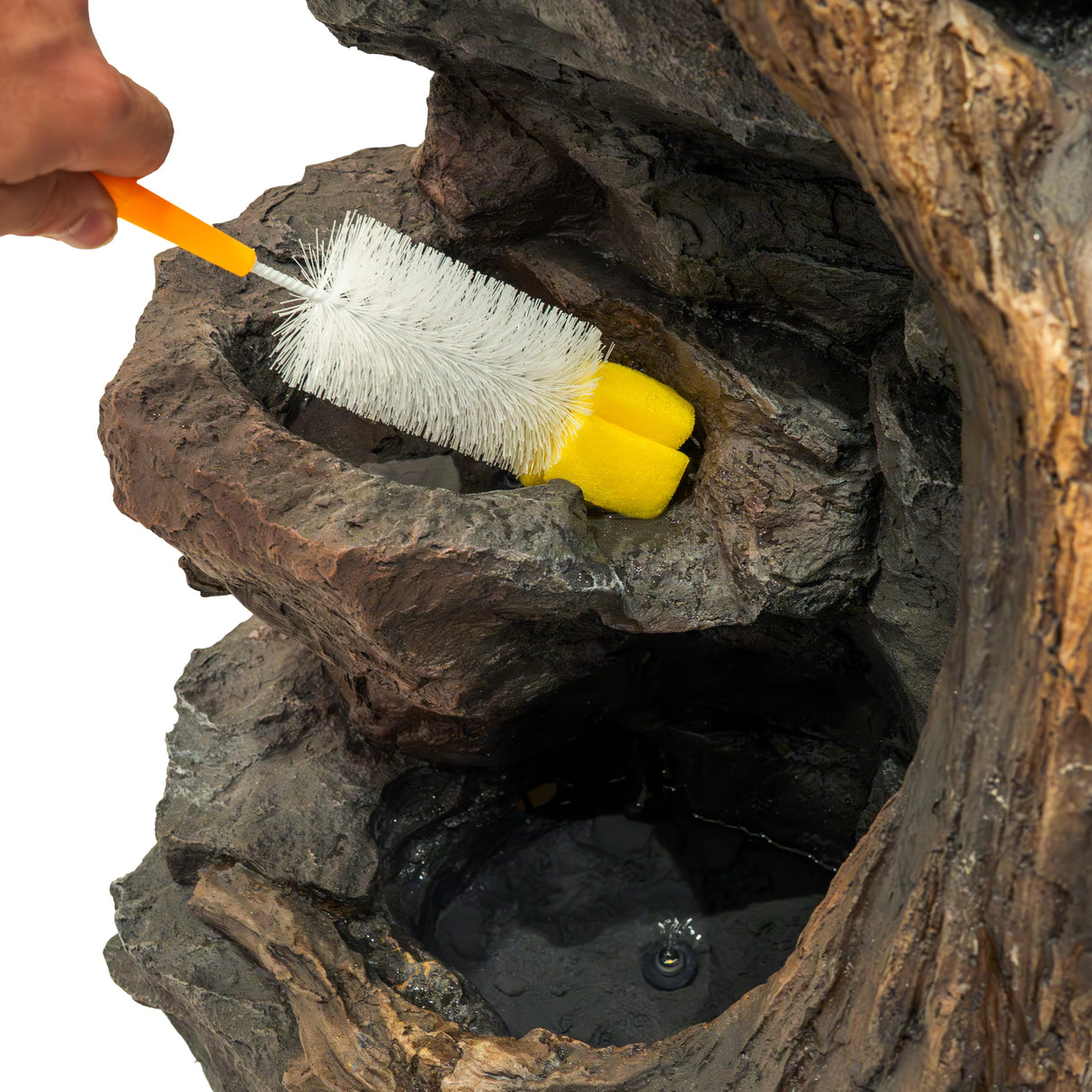 Cleaning the Electric Water Feature - Willow Springs with a brush, showcasing its textured stone finish and water basin