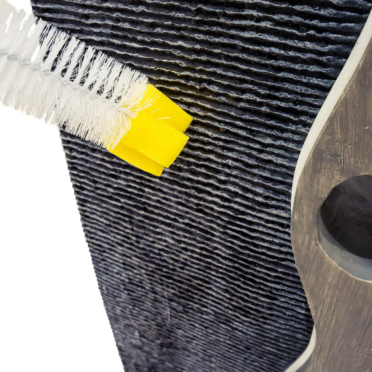 Close-up of the Harmony Falls electric water feature, showing textured black stone and a cleaning brush with a yellow handle