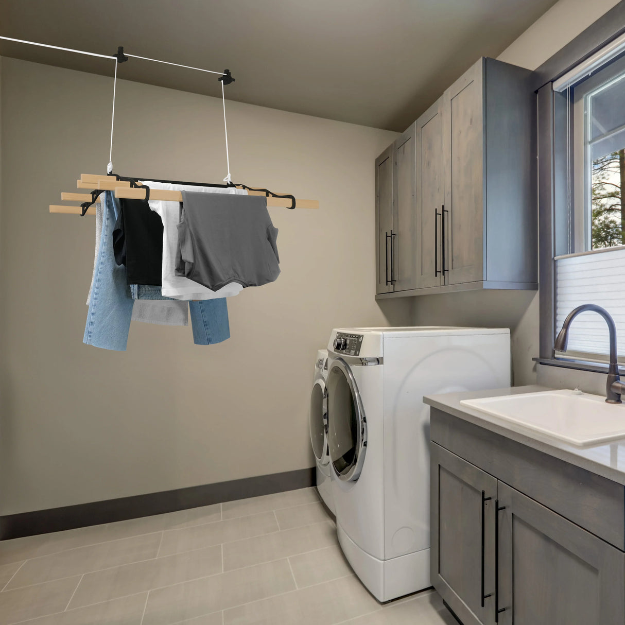 Ceiling pulley clothing airer in black, featuring hanging clothes including jeans and shirts, set in a modern laundry room