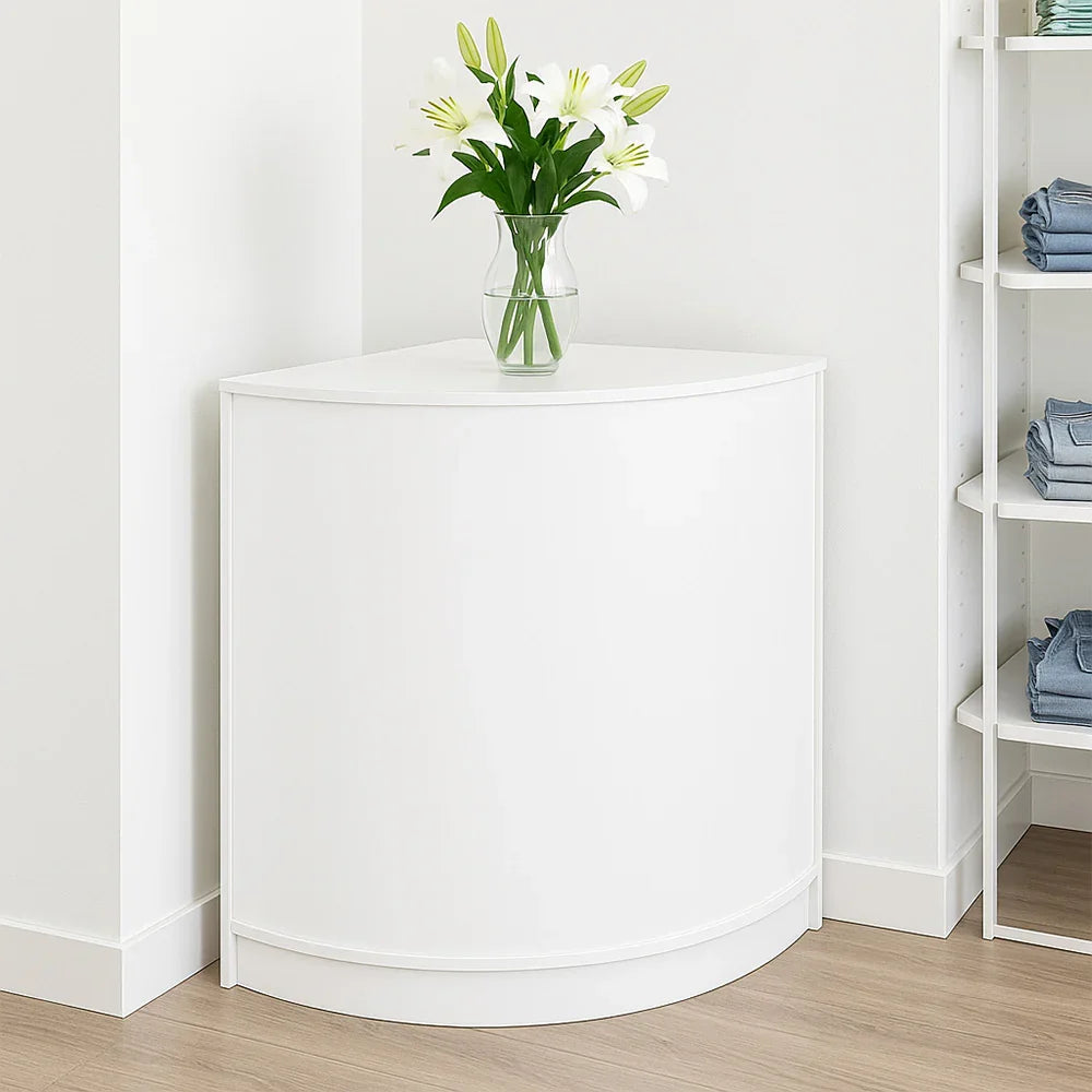 Corner retail shop counter in sleek white finish, featuring a smooth curved design, complemented by a vase of fresh lilies