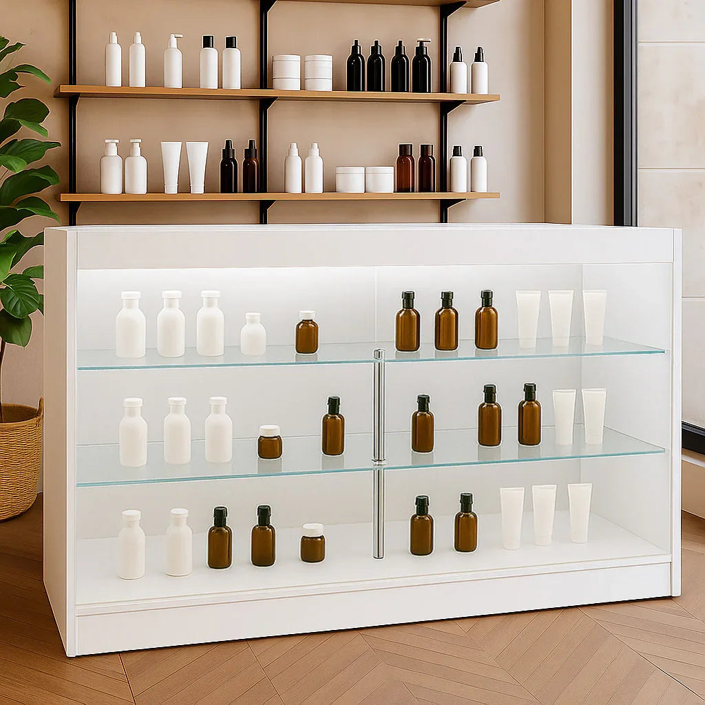 LED retail shop counter K1500 in white with glass shelves displaying various brown and white bottles against a modern backdrop