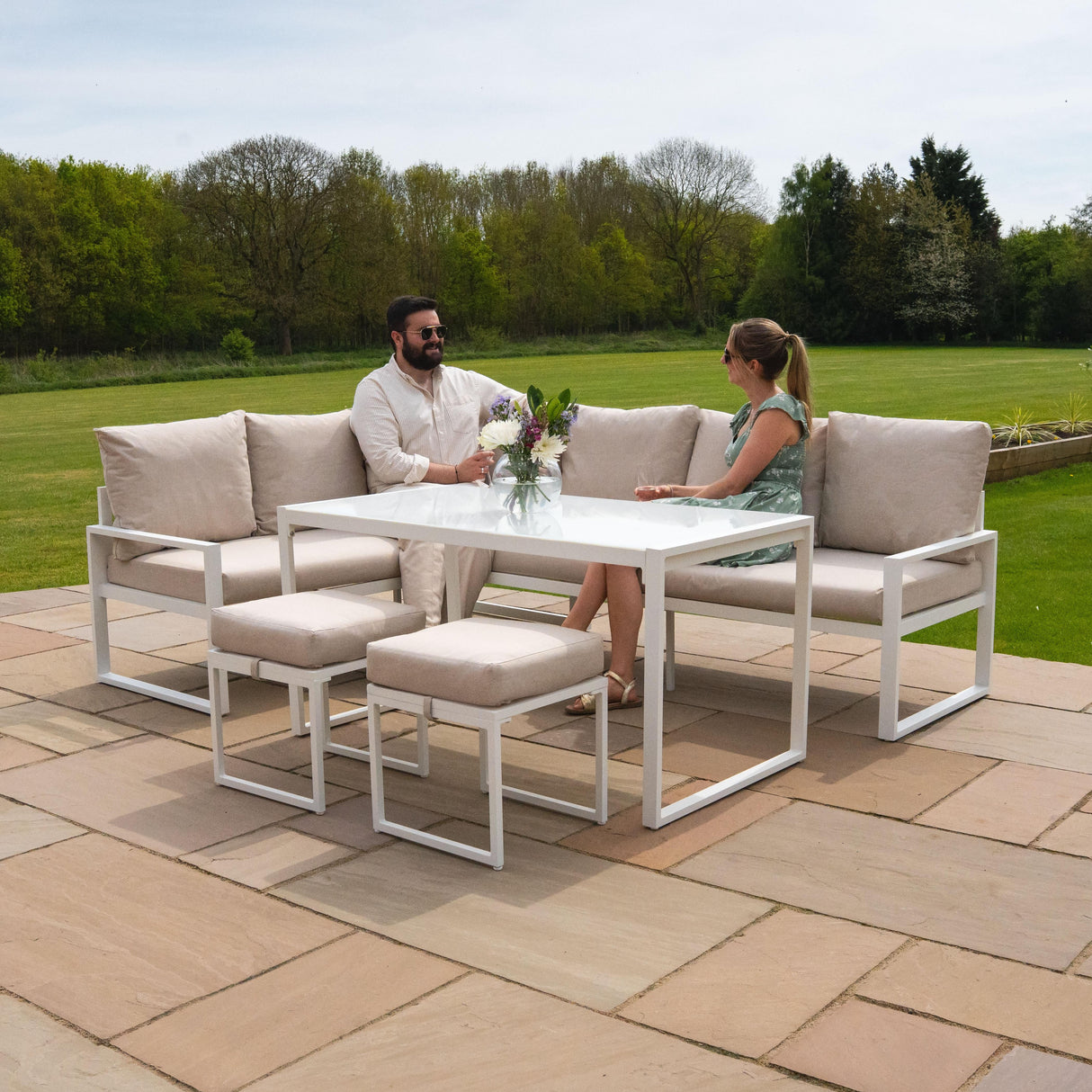 Stylish white aluminium corner sofa set with plush beige cushions, perfect for outdoor lounging, featuring a glass-top table