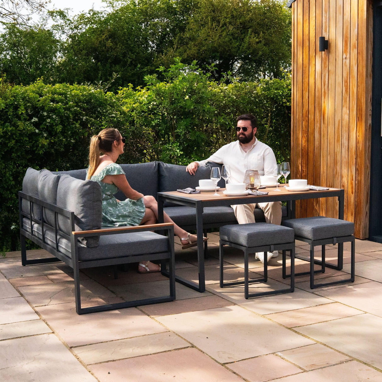 Aluminium corner sofa set with wood effect, featuring grey cushions and a sleek black frame, perfect for outdoor relaxation and dining