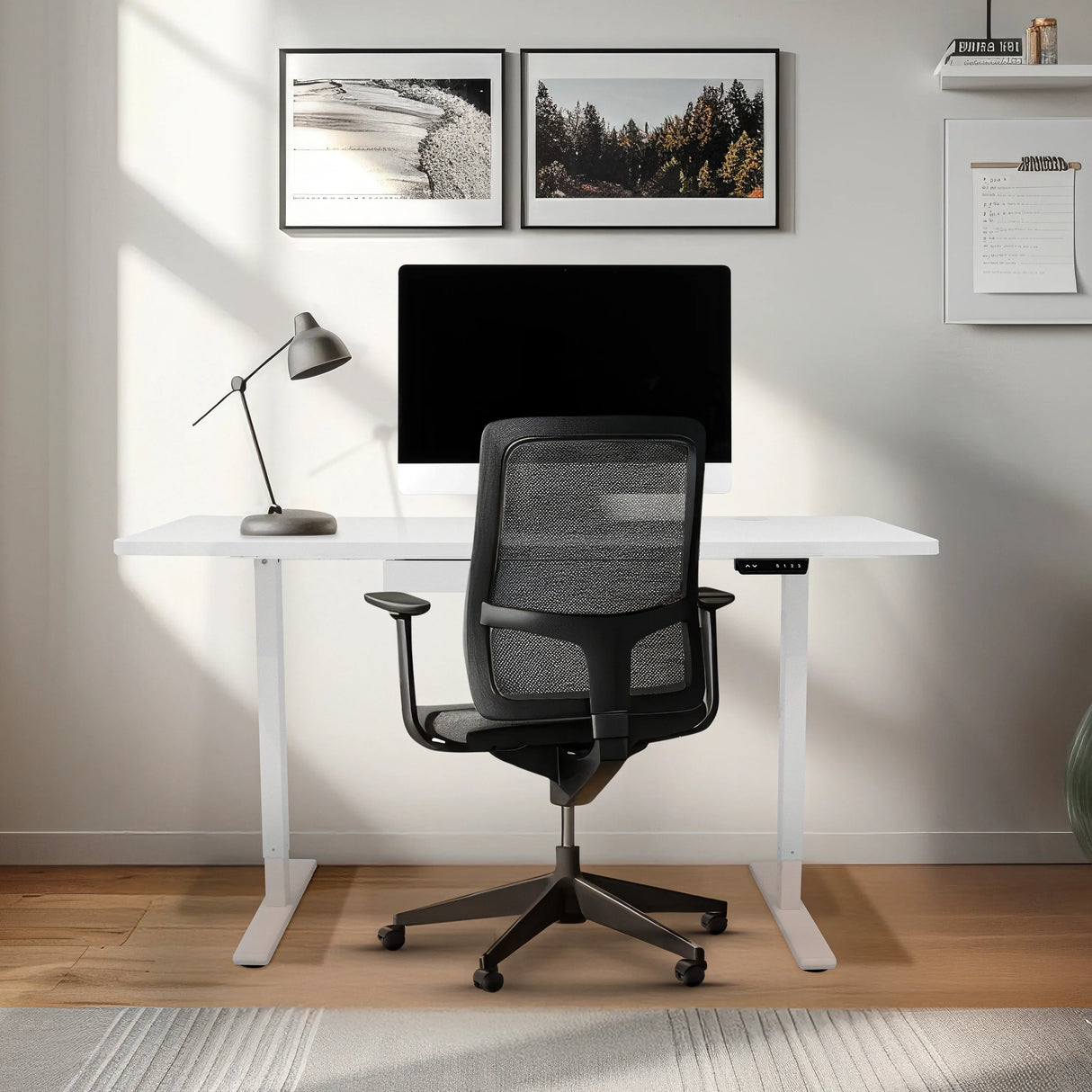 Electric standing desk with a sleek white surface, adjustable height, and a drawer, paired with a modern black office chair in a bright workspace