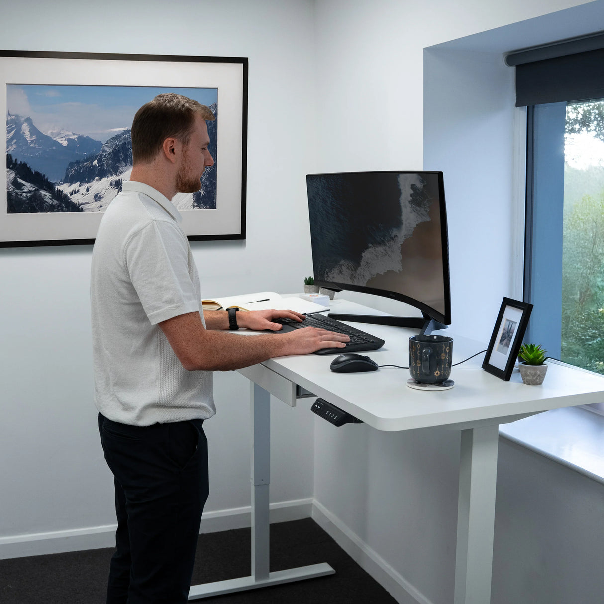 Electric standing desk with drawer, sleek white finish, adjustable height, modern design, set in a bright office with mountain view