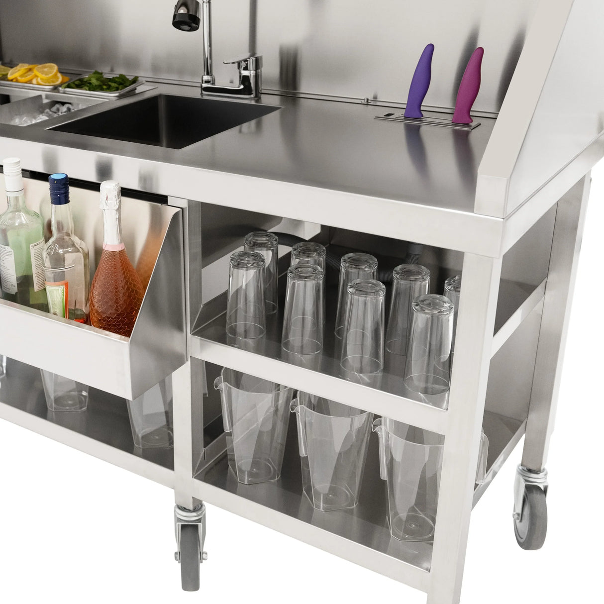 Stainless steel mobile cocktail bar station with storage for bottles, glasses, and fresh ingredients, featuring sleek design and wheels for mobility
