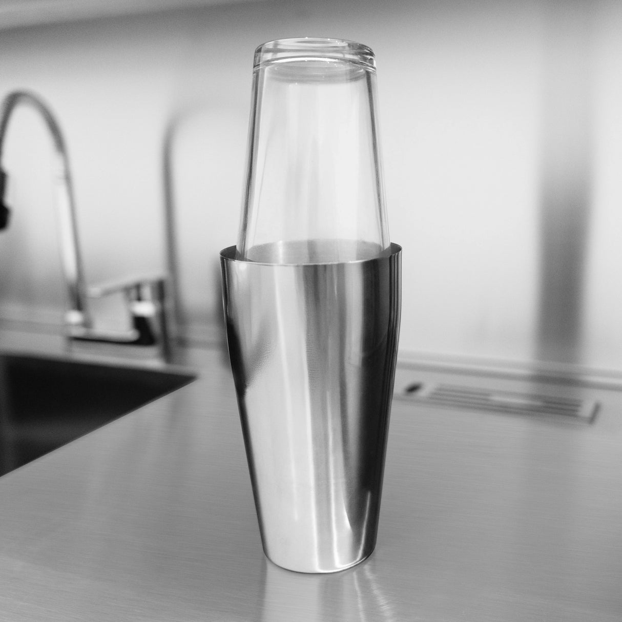 Sleek stainless steel cocktail shaker with a clear glass top, set on a modern kitchen countertop, perfect for mixology enthusiasts