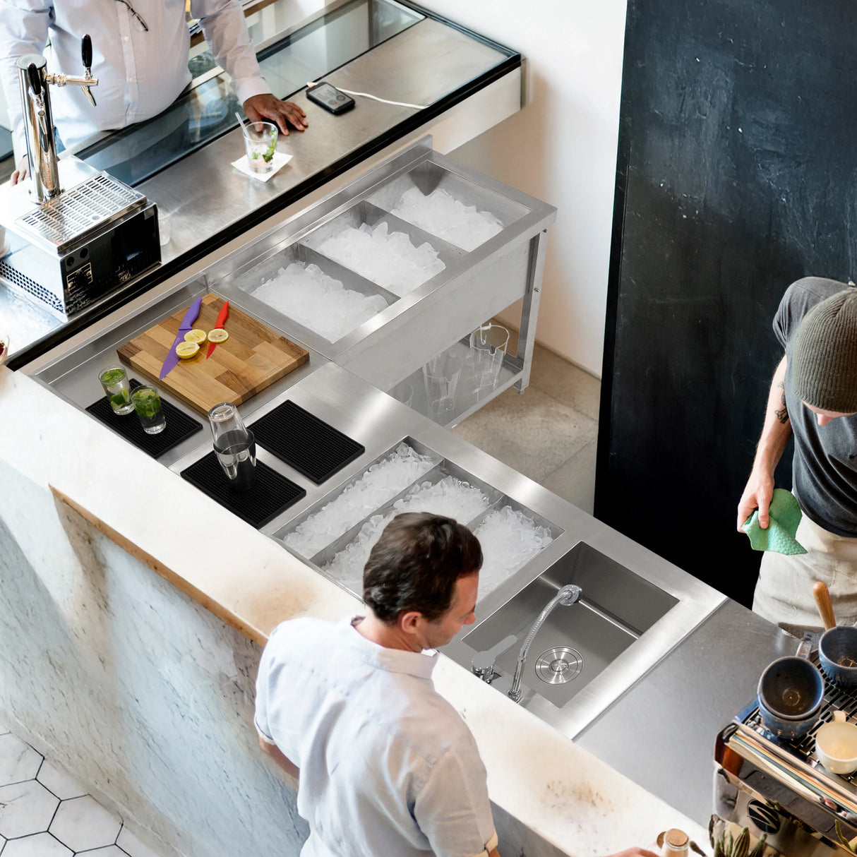 Sleek stainless steel modular cocktail bar corner unit with ice bins, cutting board, and drink preparation area in a modern setting