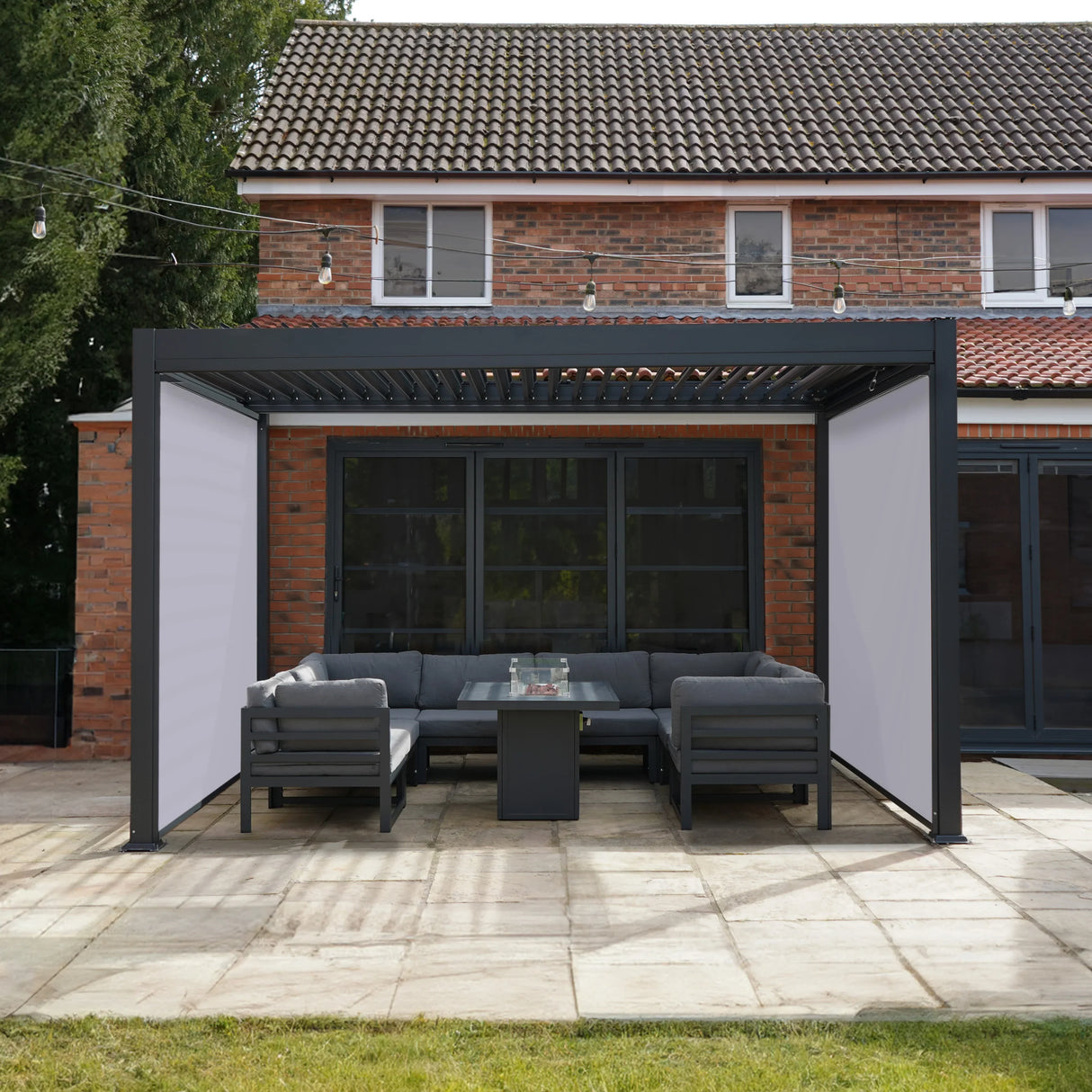 Anthracite aluminium pergola with white blinds, featuring a modern design and a cozy seating area on a patio with stone flooring