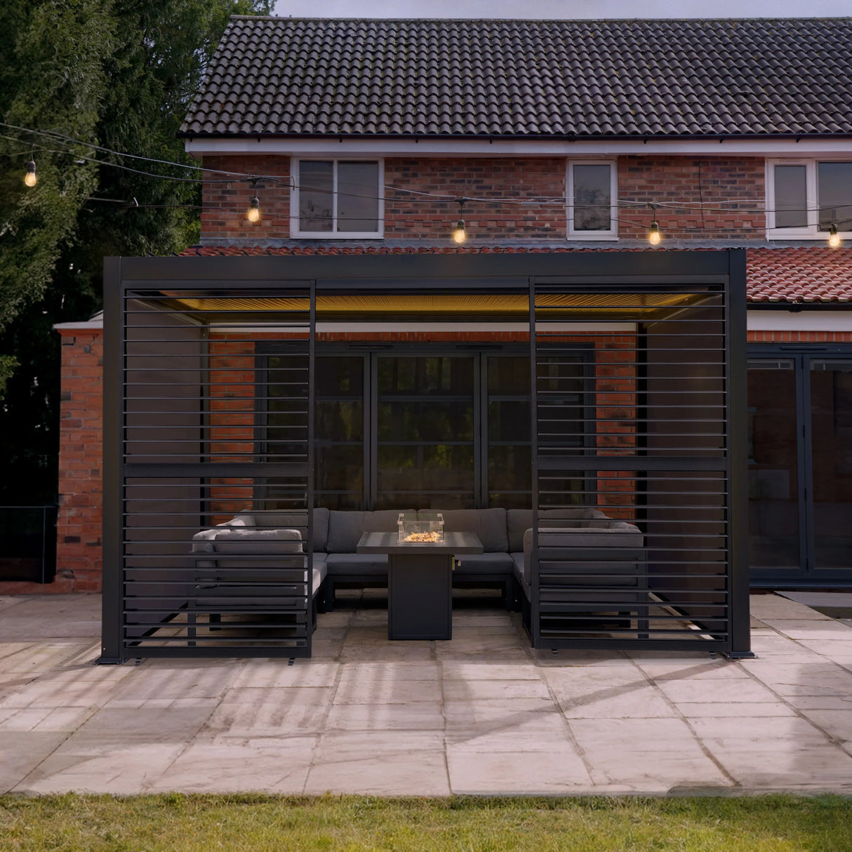 Aluminium pergola with anthracite blinds, two side panels, LED lights, and a cozy seating area on a patio with a modern design