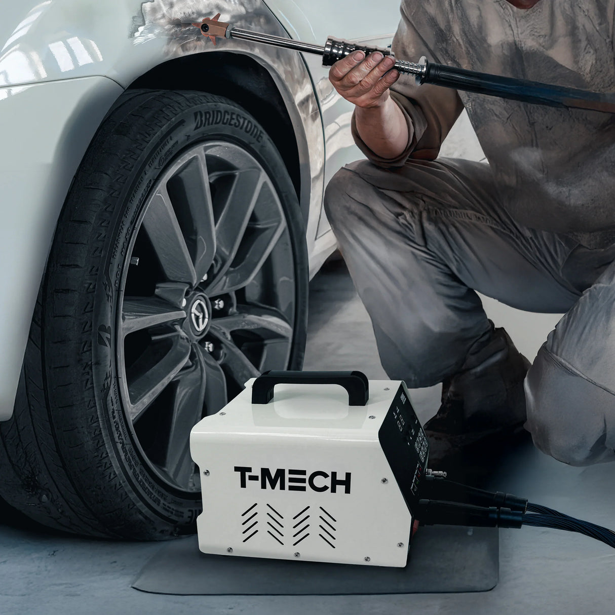 T-MECH dent puller machine with a sleek white design, positioned near a car tire, showcasing its professional repair capabilities