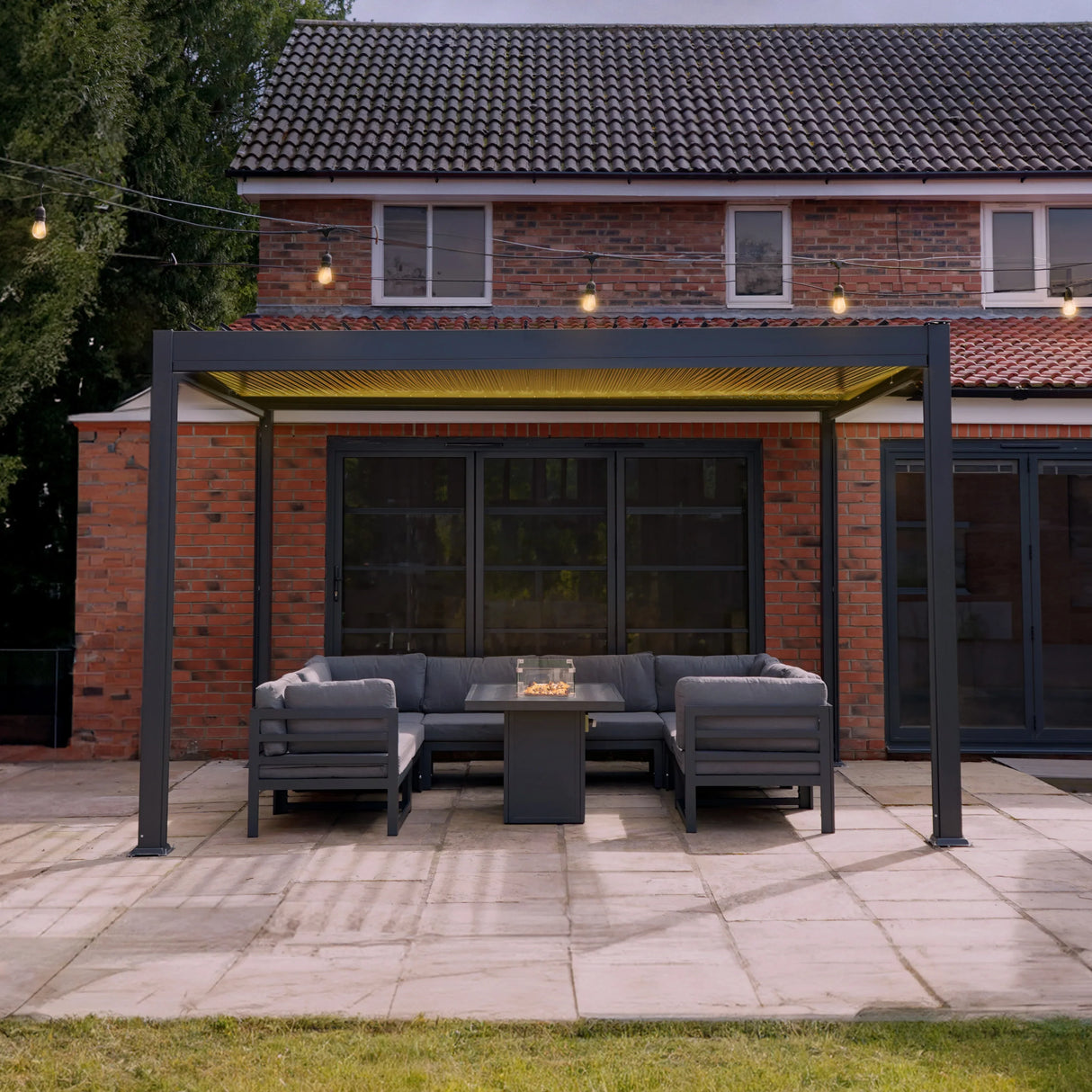 Anthracite aluminium pergola with integrated LED lights, featuring a sleek design, surrounded by outdoor seating and a patio area