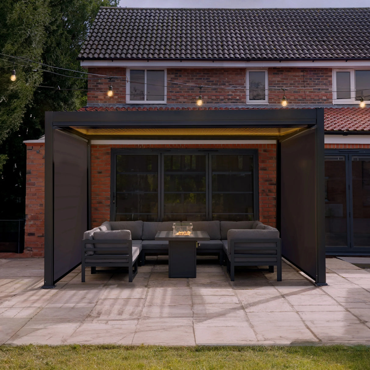 Aluminium pergola with anthracite blinds and integrated LED lights, featuring a modern design and spacious seating area in a backyard setting