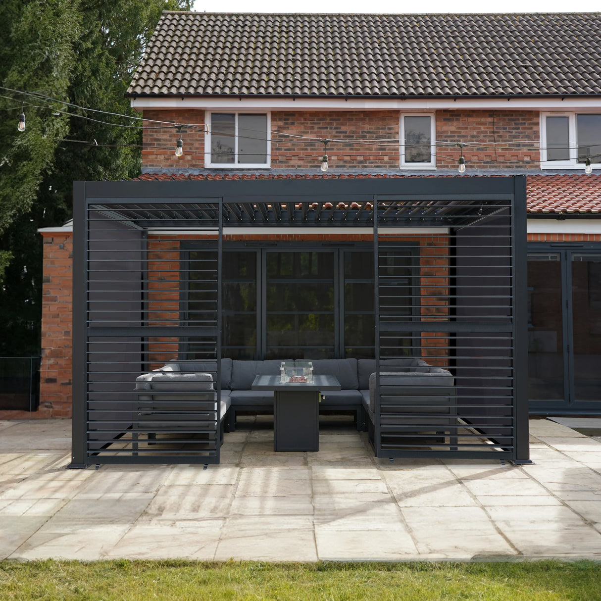 Aluminium pergola with anthracite blinds and two shutter panels, featuring a modern design and a cozy outdoor seating area