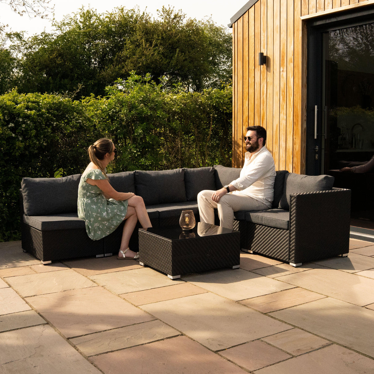 Rattan modular 7-piece furniture set in black with plush gray cushions, featuring a spacious sectional and coffee table, ideal for outdoor lounging