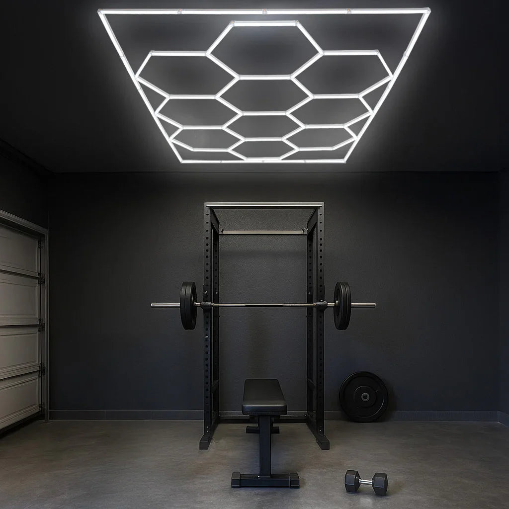 Hexagon LED lighting fixture in a modern gym, illuminating a weight bench and barbell against a sleek dark wall backdrop