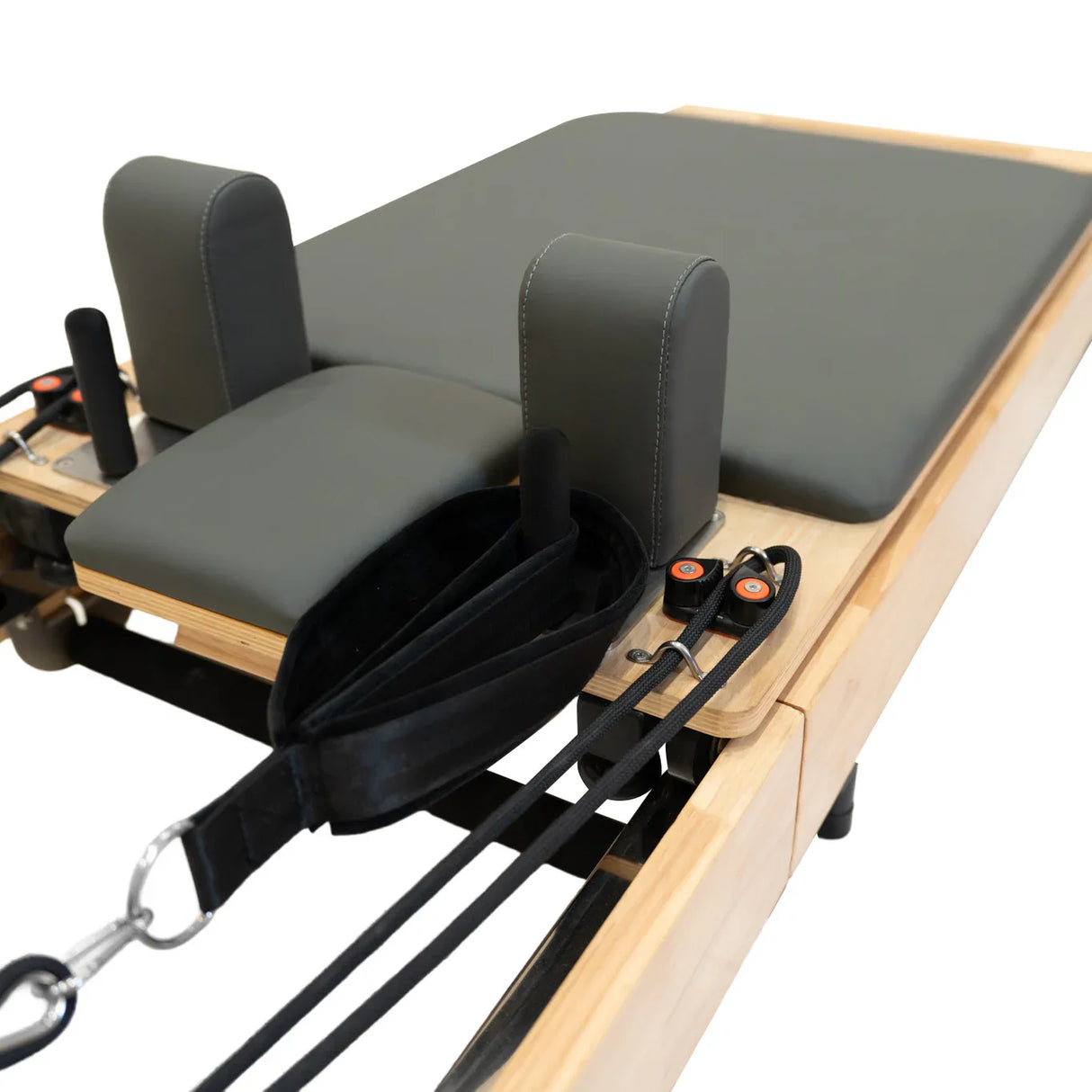 Oak Pilates reformer machine featuring a padded gray platform, adjustable straps, and sturdy construction for versatile workouts