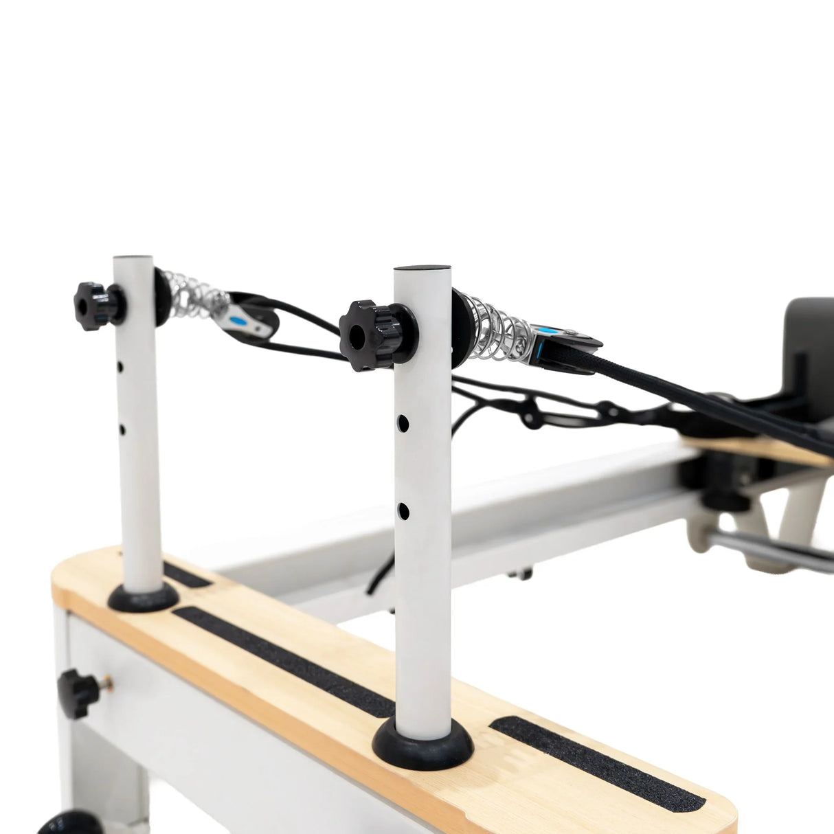 Aluminium Pilates reformer machine with adjustable vertical posts, black rubber feet, and smooth wooden surface for stability and comfort