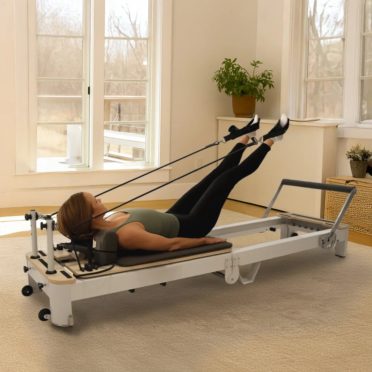 Aluminium Pilates reformer machine with a padded platform, resistance cords, and a person performing leg exercises in a bright room