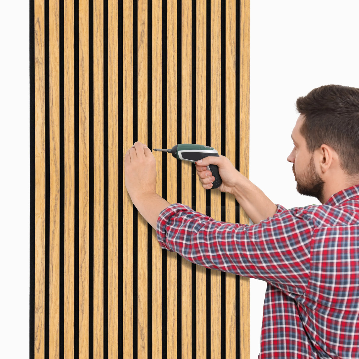Acoustic slat wall panels in oak, featuring vertical slats, being installed by a man using a power drill against a white background