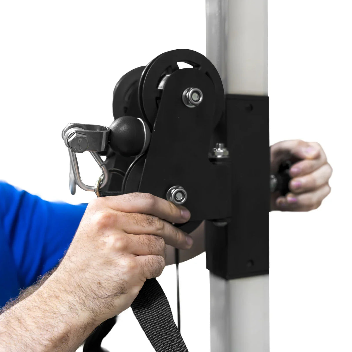 Wall mounted cable pulley machine with a black pulley system, adjustable strap, and a hand gripping the mechanism for easy use